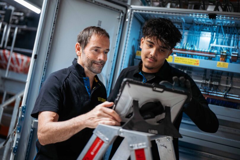 Zwei Elektrofachkräfte kontrollieren und testen einen installierten Schaltschrank